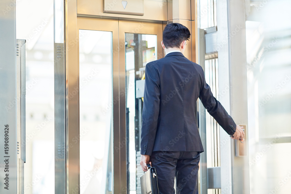Businessman touching button by the door to make it open Businessman touching button by the door to make it open