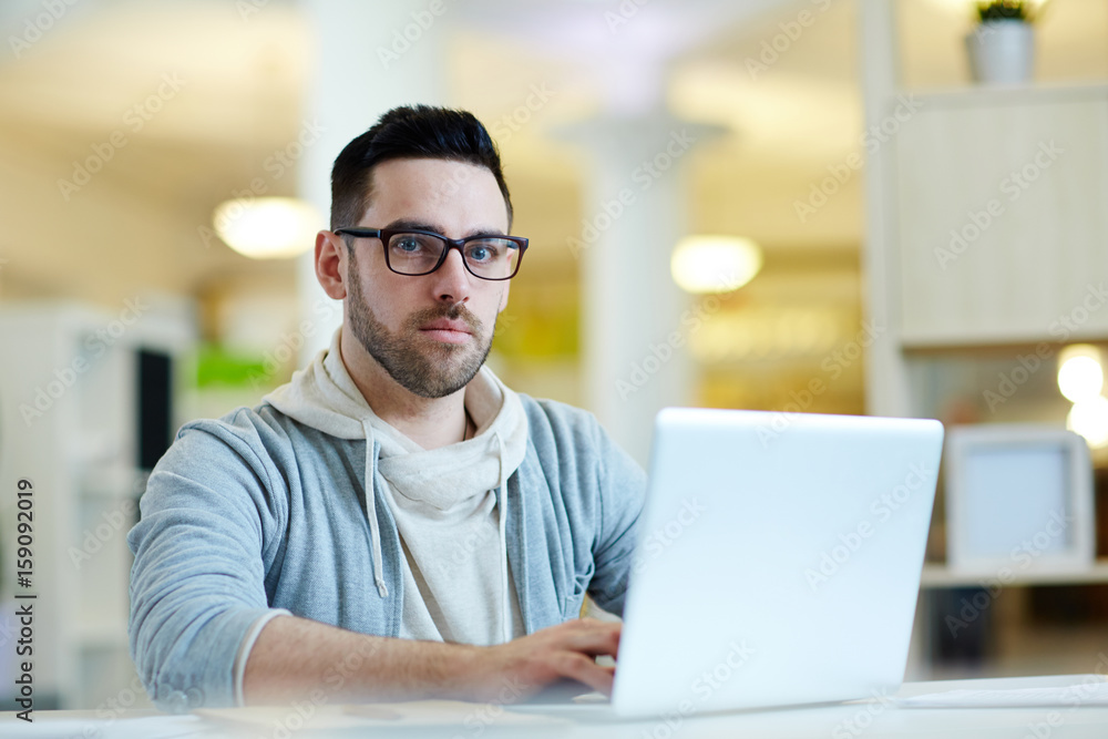 Pensive businessman sitting by workplace and typing Pensive businessman sitting by workplace and typing