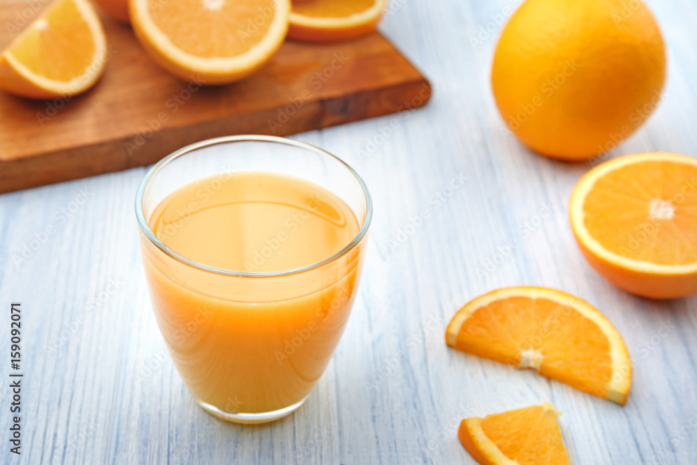 Glass of fresh orange juice and fruit slices on white wooden background Glass of fresh orange juice and fruit slices on white wooden background
