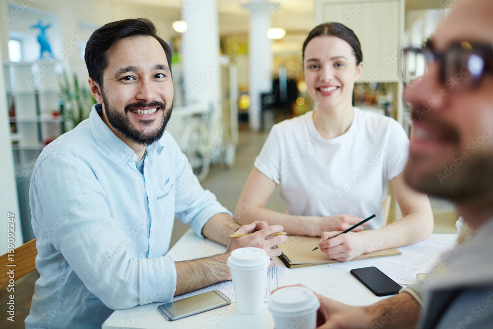 Young team sitting by workplace and brainstorming Young team sitting by workplace and brainstorming