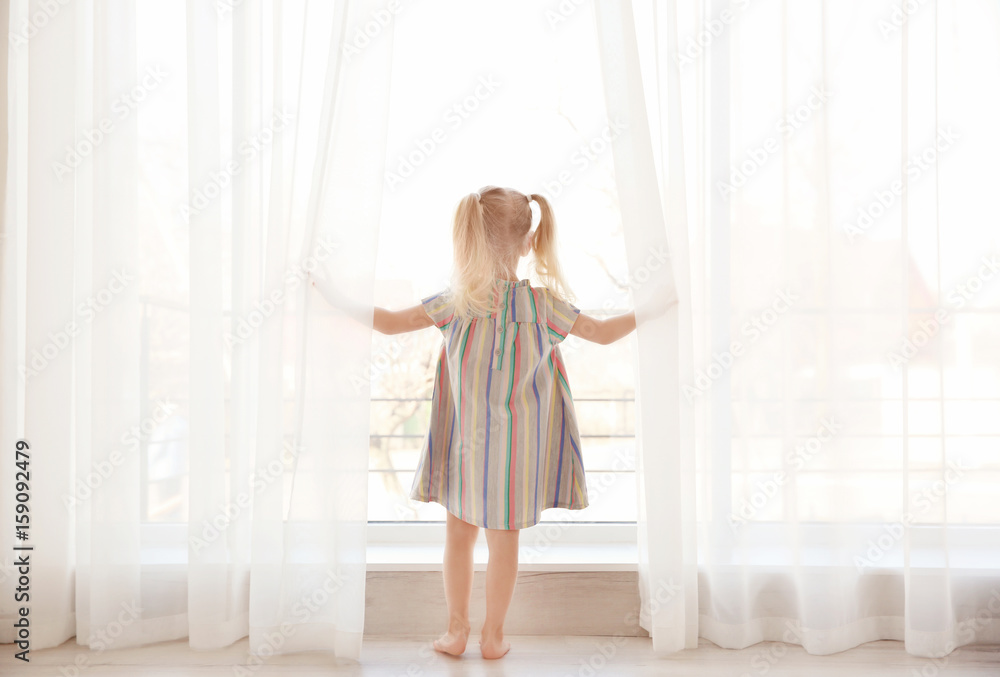 Cute little girl standing near windowsill Cute little girl standing near windowsill