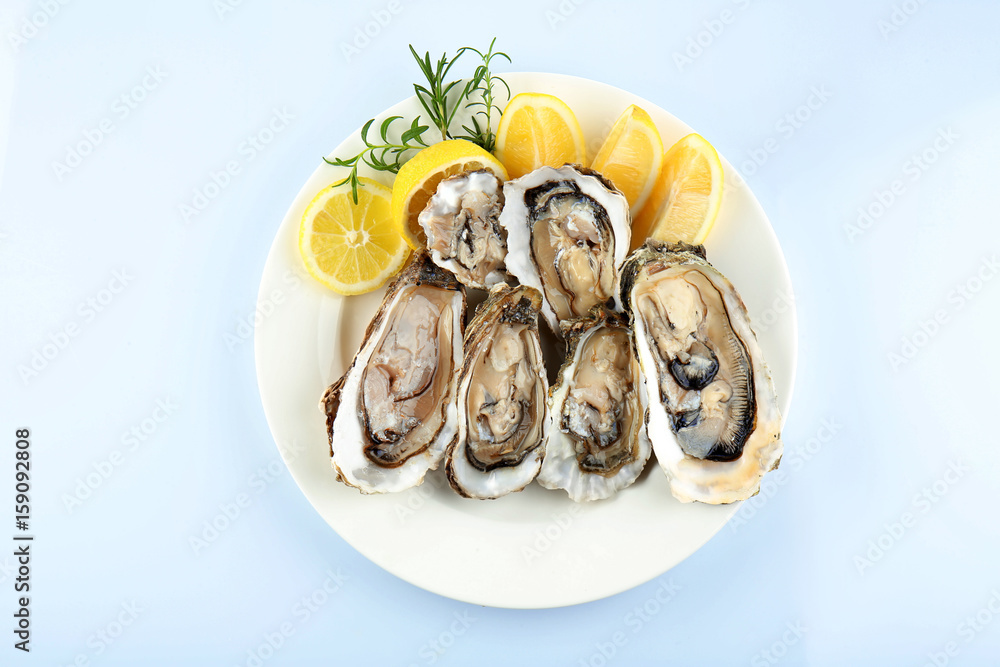 Plate with tasty fresh oysters and sliced juicy lemon on white background. Aphrodisiac food for increasing sexual desire Plate with tasty fresh oysters and sliced juicy lemon on white background. Aphrodisiac food for increasing sexual desire