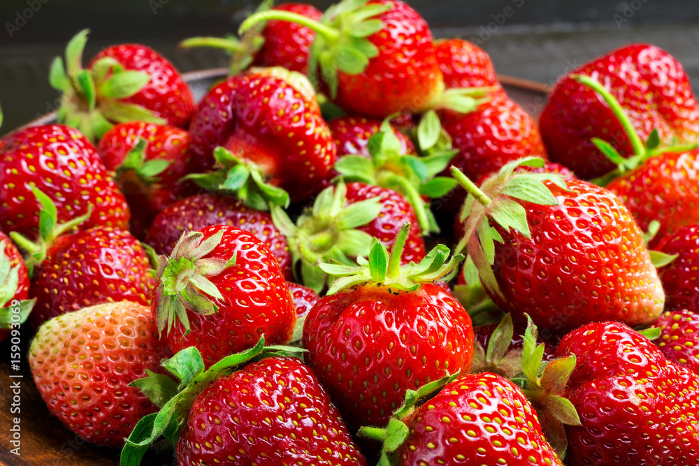 Fresh organic strawberries in plate on dark wooden planks background Fresh organic strawberries in plate on dark wooden planks background