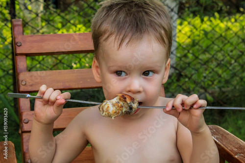 Tubby boy with pleasure eats a shish kebab. Camping. Healthy nutrition and diet. summer picnic.