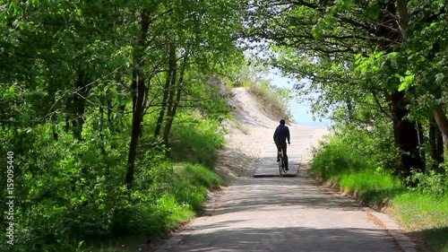 Man riding bicycle on boardwalk away to the beach, photo