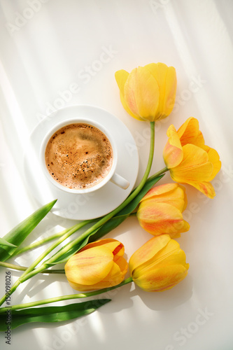 Beautiful tulip flowers and cup of coffee on light background