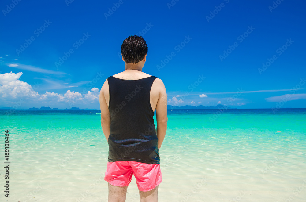 backside of man with black vest and pink shorts on blue sea background