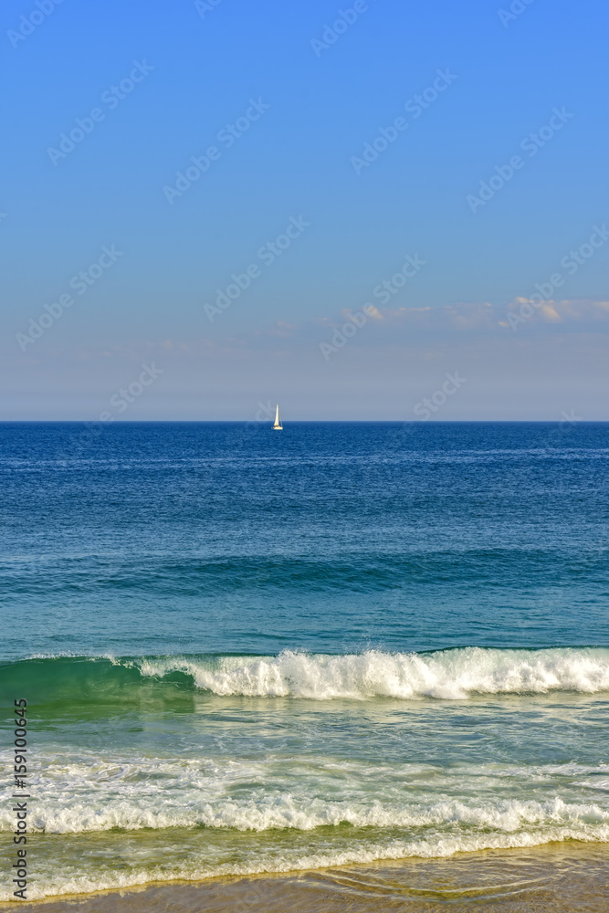 Sailboat at horizon line of the blue waters on Ipanema beach at Rio de Janeiro