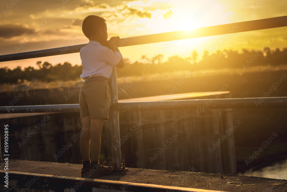 Fototapeta premium Student boy stand on bridge at sunset.