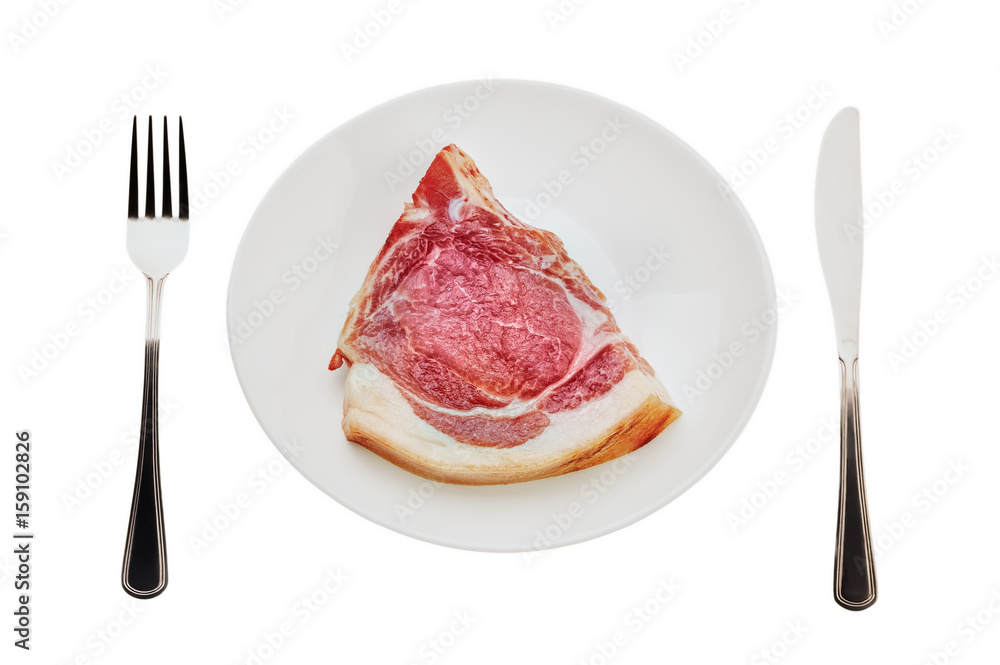 A piece of raw pork on a white plate with a knife and fork. Isolated on white background. A piece of raw pork on a white plate with a knife and fork. Isolated on white background.