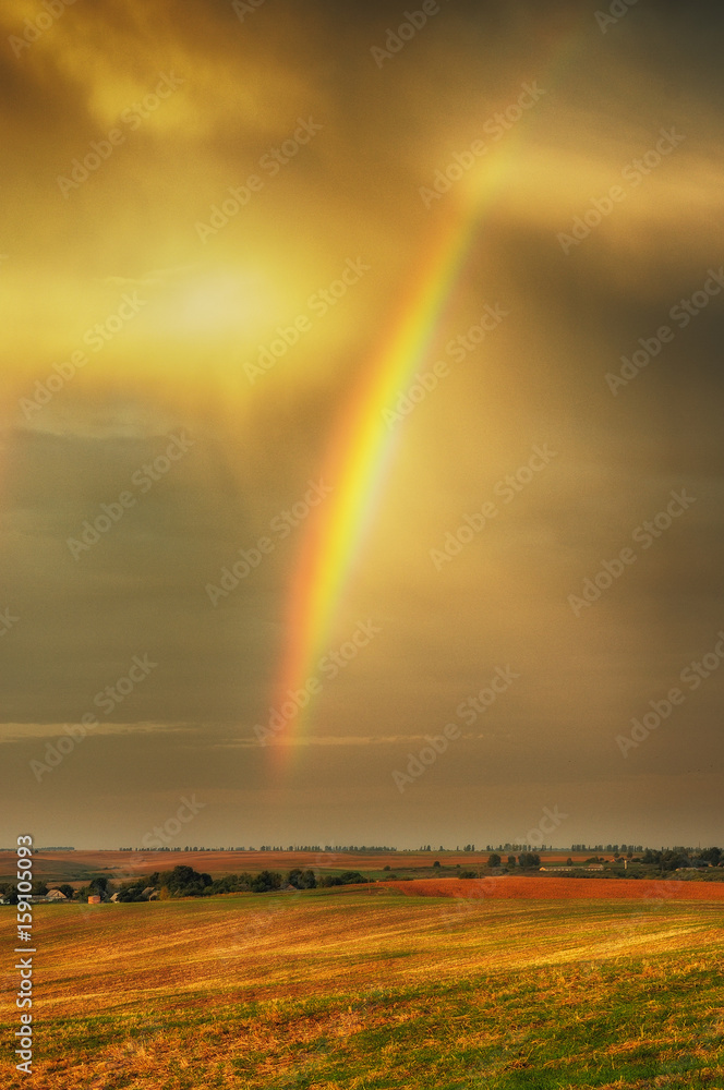 rainbow. Autumn dawn. Cloudy sky over the picturesque field