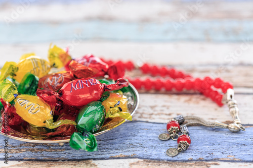 Colorful candies and red rosary on vintage table photo