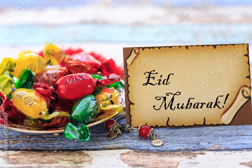 Eid mubarak  on the card with colorful candies on vintage table photo