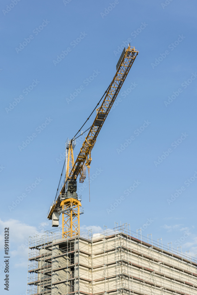 Fototapeta premium Construction crane and top of the building with scaffolding.