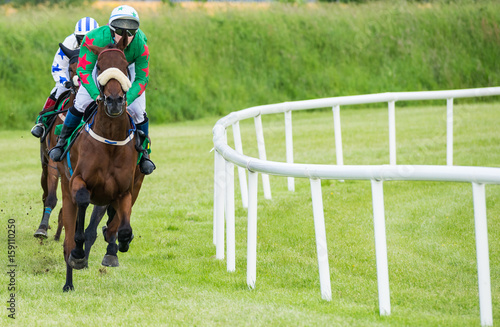 Jockey and race horse in first position taking the final turn towards the finish line