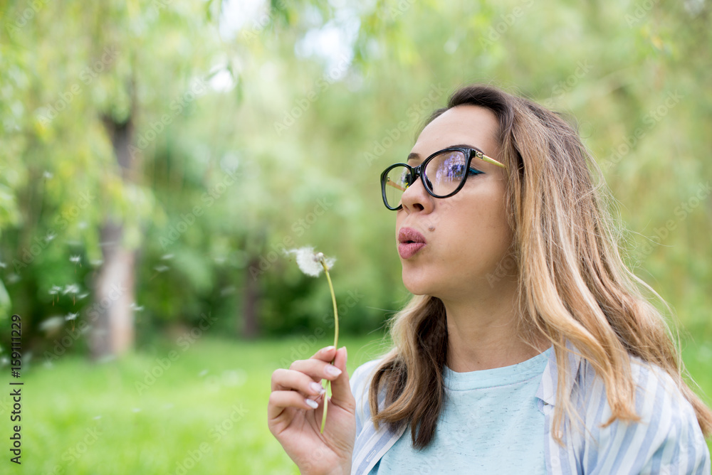 Portrait of beautiful young woman blowing dandelion flower Portrait of beautiful young woman blowing dandelion flower