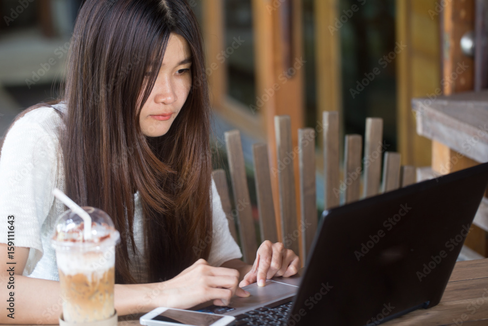 Women use laptop with ice coffee on wood table Women use laptop with ice coffee on wood table
