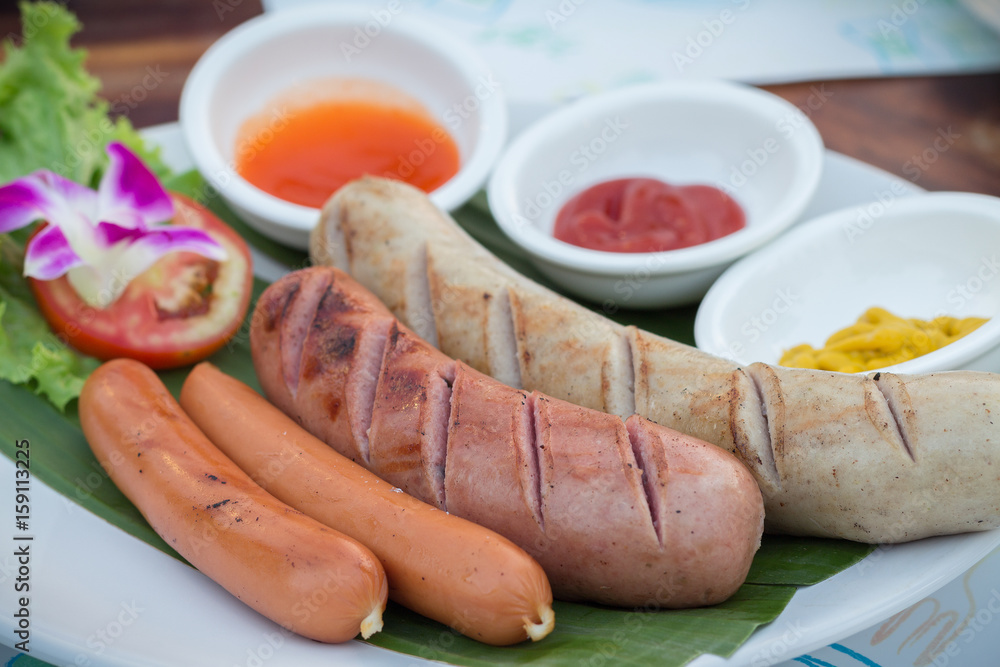 Grilled sausages and vegetables. Grilled pork sausages. Sausages serve with spicy sauce.Delicious german sausages.(selective focus) Grilled sausages and vegetables. Grilled pork sausages. Sausages serve with spicy sauce.Delicious german sausages.(selective focus)