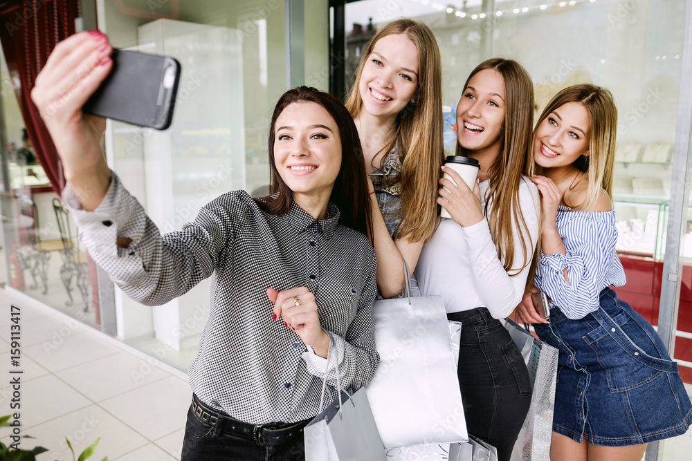 Fototapeta premium Four beautiful girls doing selfie in shopping center