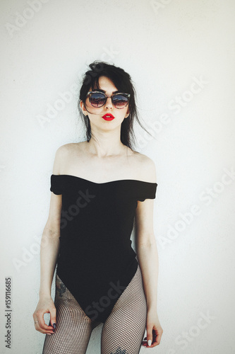 Sexy girl or female sex, in a sexy body suit is seductive in sunglasses, with sunlight. With pantyhose in a mesh