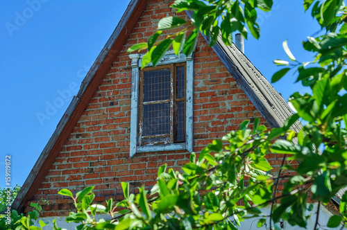Green old attic on the roof. The roof of the old house against the blue sky