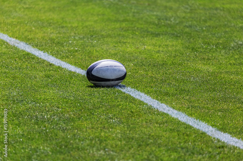 Rugby ball on green pitch and white line
