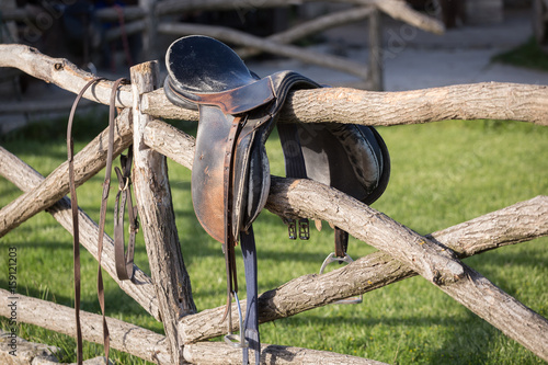 Vintage saddle on rural fence. Ranch scene
