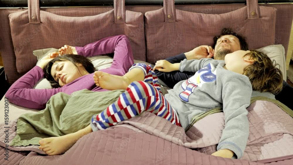 Husband and wife sleeping in the morning with kid lying on them