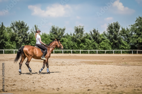 Female riding a horse in outdoor equestrian arena