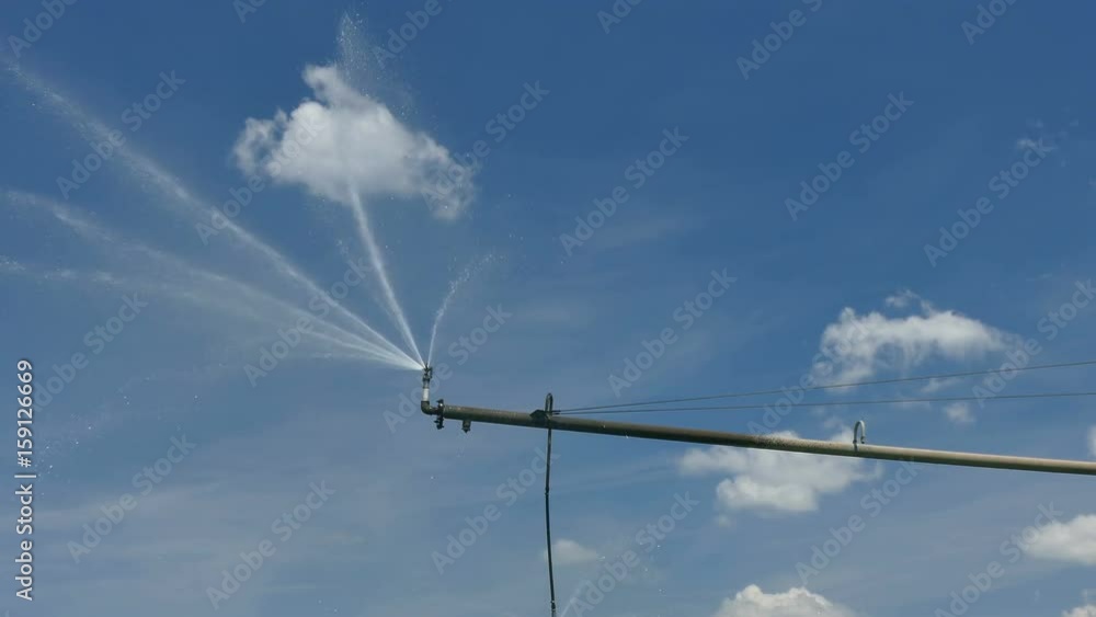 Irrigation system sprinkler for water supply over blue sky and clouds