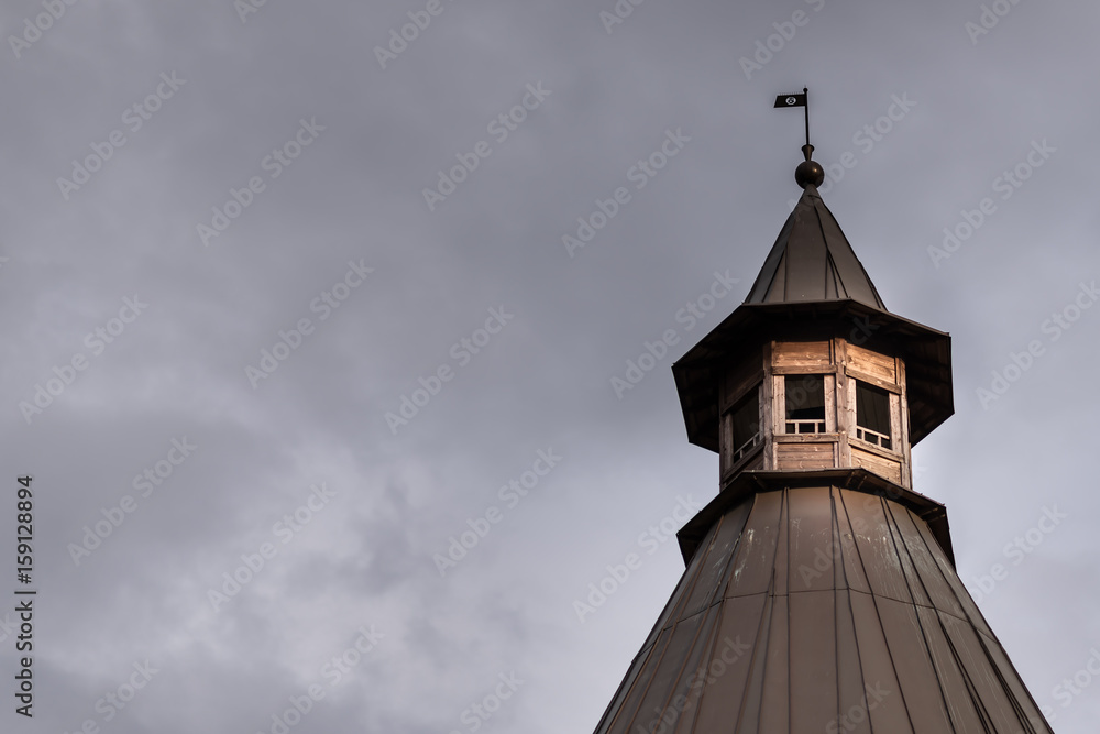 Wooden tower with a pointed octagonal roof against a blue sky