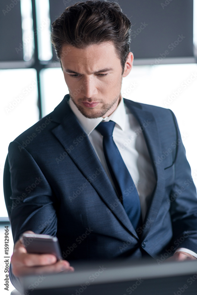 Stylish young man in suit is reading information on phone Stylish young man in suit is reading information on phone