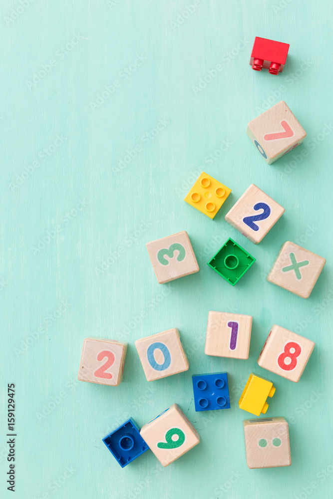 Wooden cubes with numbers and colorful toy bricks on a turquoise wooden background. Wooden cubes with numbers and colorful toy bricks on a turquoise wooden background.