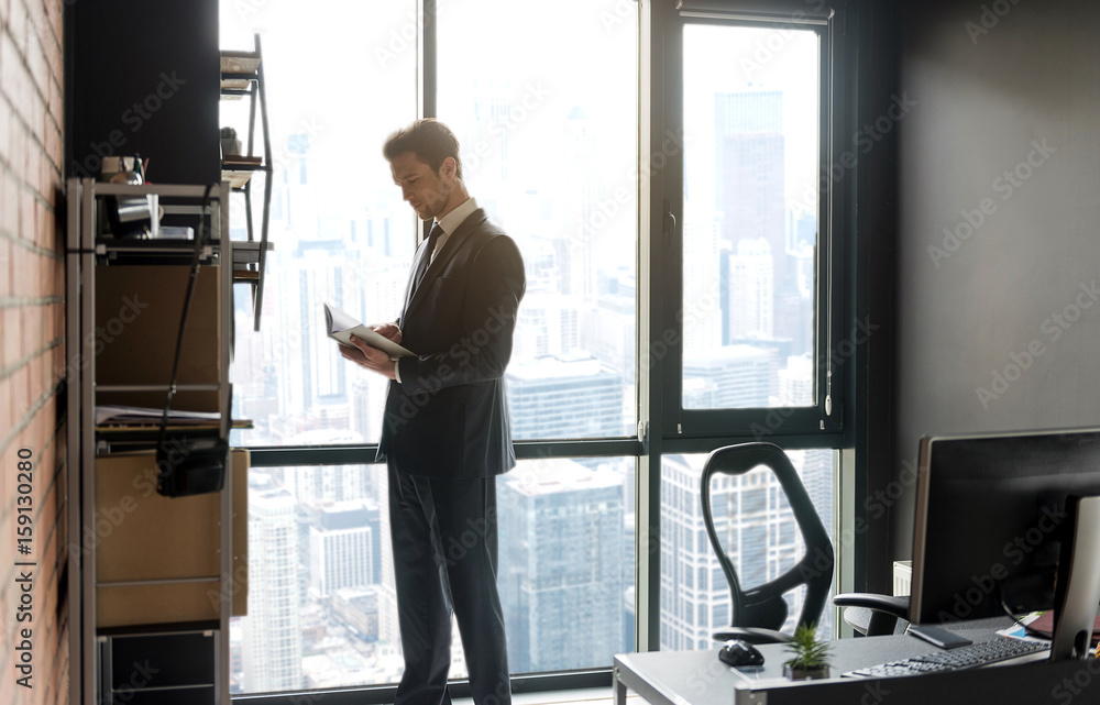 Fototapeta premium Young businessman in suit is enjoying literary work