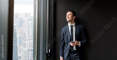 Cheerful pleasant businessman is standing in office