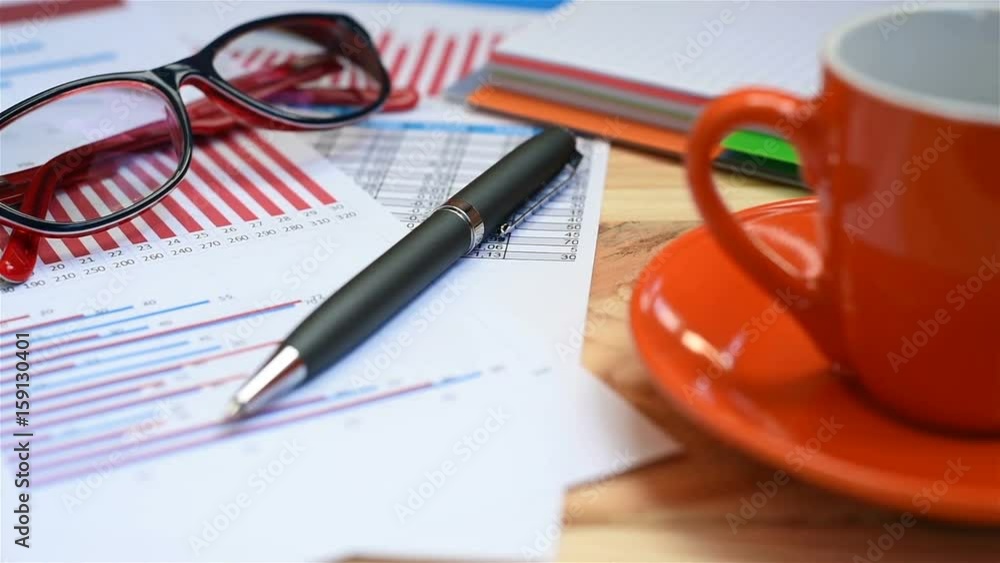 Investment Charts And Stock Statistics, Mobile Phone, Pen And Cup Of Coffee Investment Charts And Stock Statistics, Mobile Phone, Pen And Cup Of Coffee