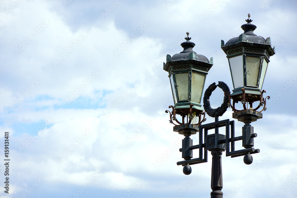 Beautiful old vintage lantern on the sky background in the city park