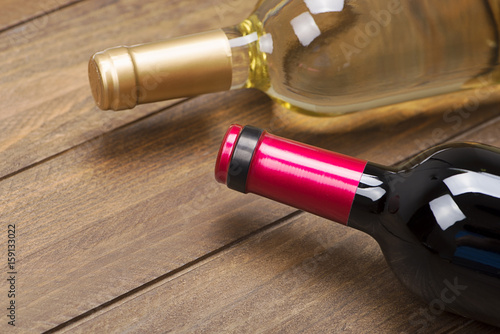 Close up of two wine bottles on brown wooden table.