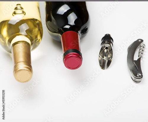 Corkscrew next to two bottles of white wine on white background. Isolated. Vertical studio shoot.
