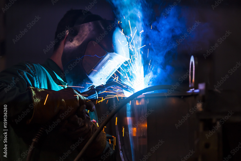 Young industrial worker welding in the factory Young industrial worker welding in the factory