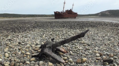 Rusty wreckage shipwreck and anchor on deserted shore beneaped dried-up ocean.Unique history place for tourism. photo