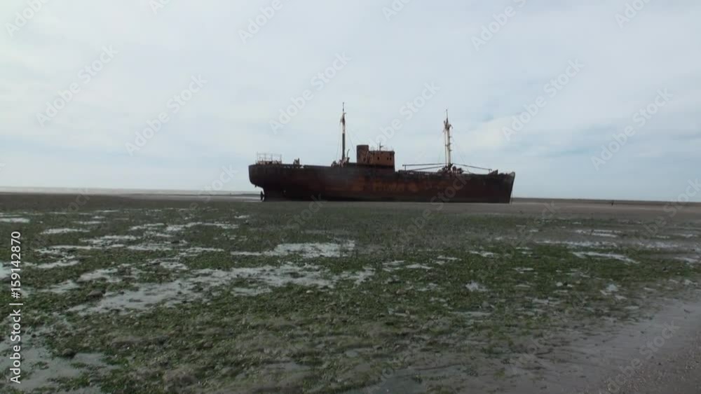 Rusty wreckage shipwreck on deserted shore beneaped dried-up ocean. Unique history place for tourism.