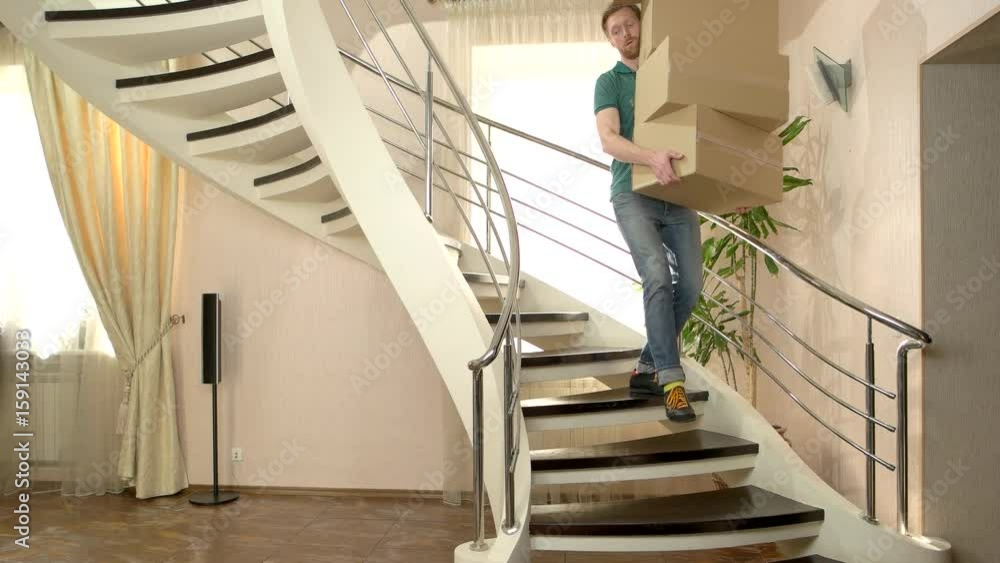 Man carrying stack of boxes. Young male walking downstairs. Common