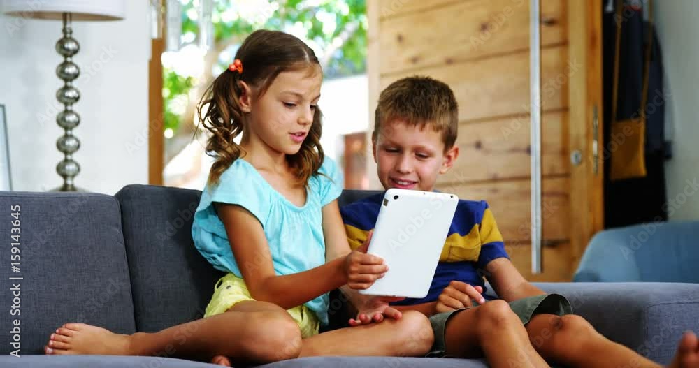 Siblings using digital tablet in living room Stock Video | Adobe Stock
