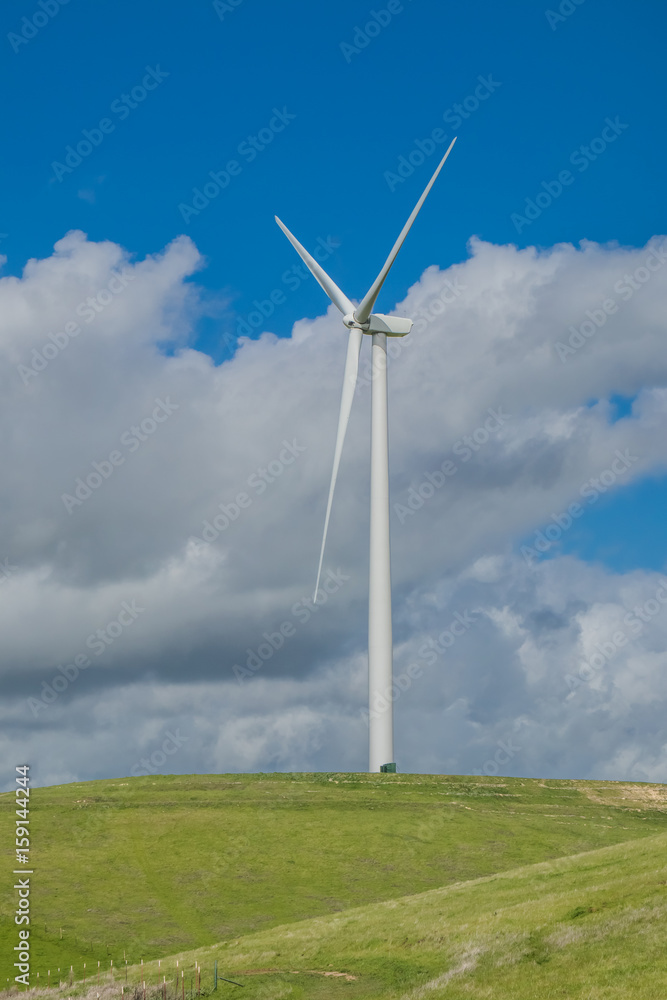 A single wind turbine on a hillside, against the backdrop of cloud-filled blue sky in the Livermore, California wind farm A single wind turbine on a hillside, against the backdrop of cloud-filled blue sky in the Livermore, California wind farm