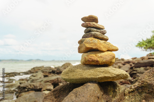 stacking of rock with blur sky and sea background 