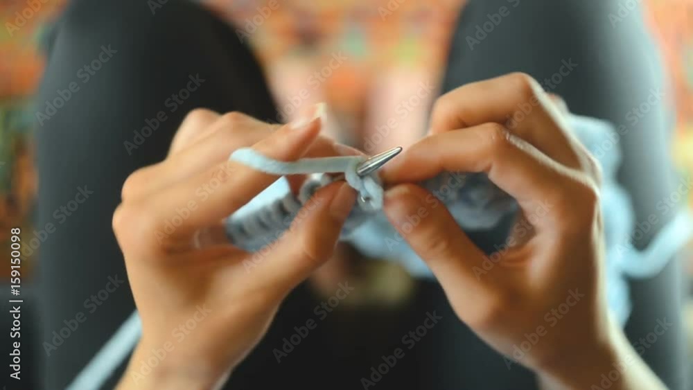 The concept of needlework - a young woman knits with circular knitting needles. Top view. Close-up The concept of needlework - a young woman knits with circular knitting needles. Top view. Close-up