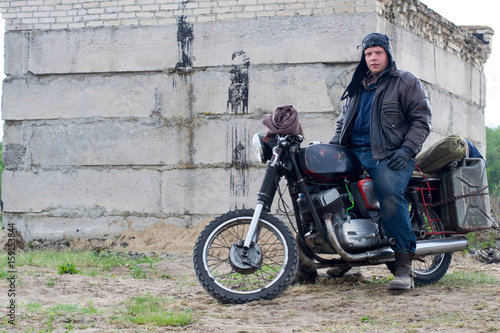 A post apocalyptic man on motorcycle near the destroyed building