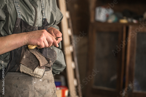 male carpenter working with a wood product, hand tools