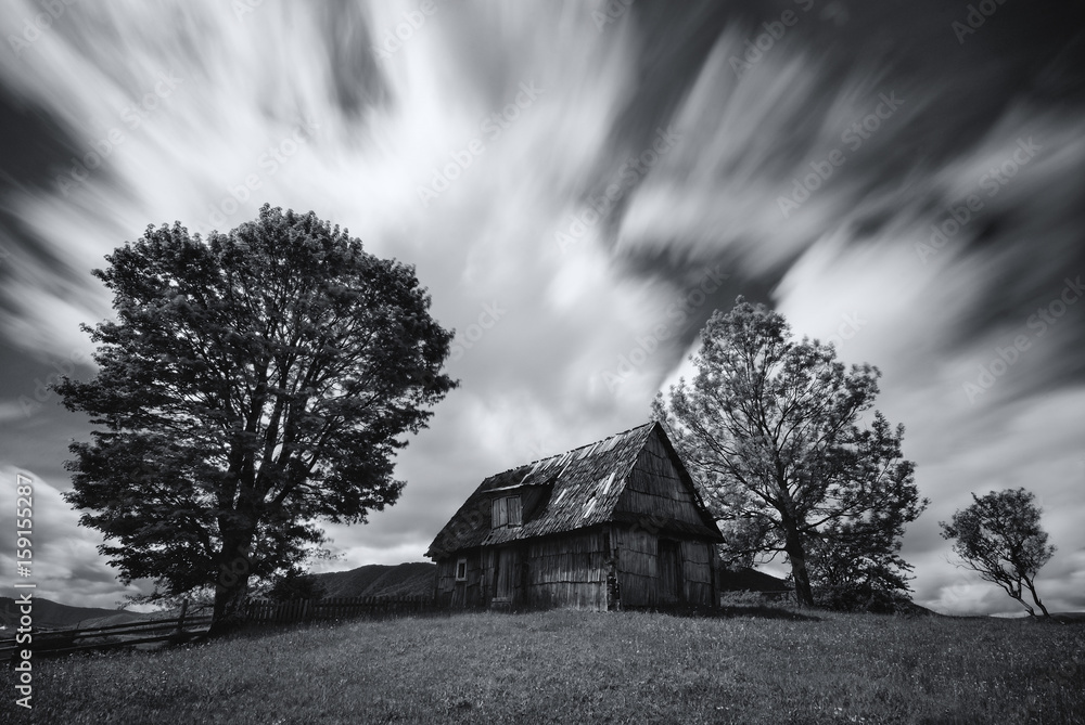 Abandoned house in West Ukraine.Old spooky abandoned farm house in black-white color.An old, long-abandoned house,against the background of a cloudy sky, shot on a long exposure.Carpathian Mountains